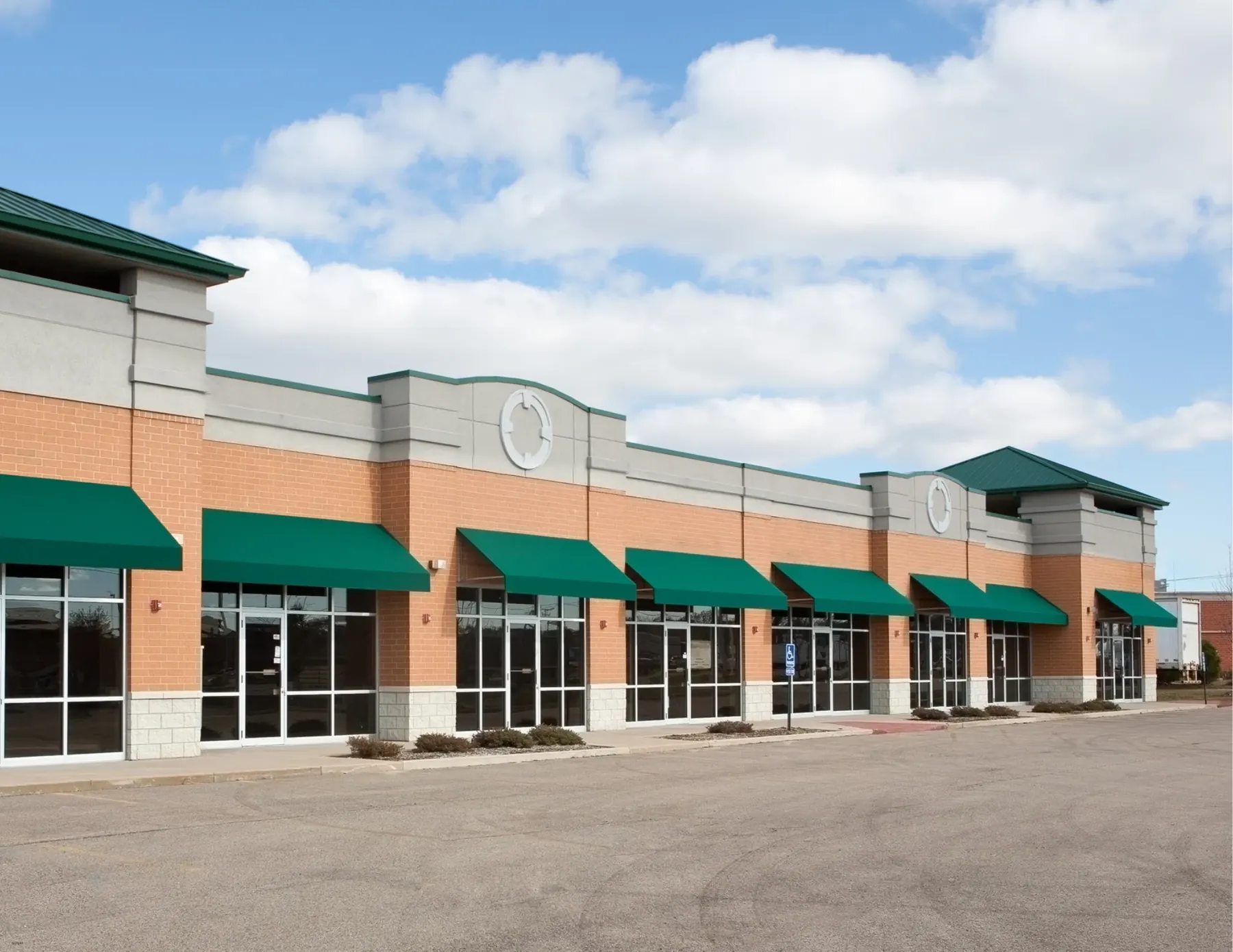 Row of brick storefronts with green awnings and units above