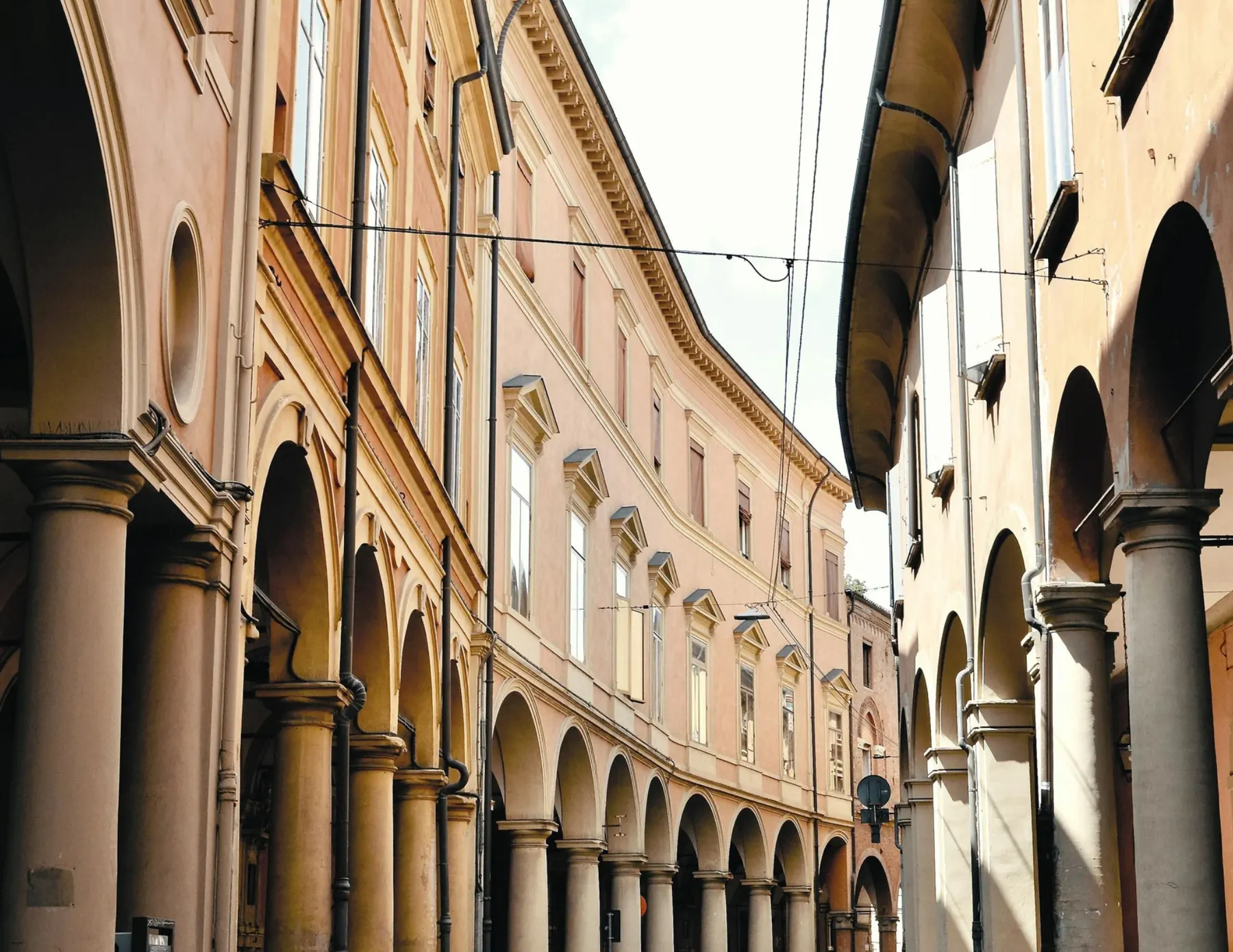 Sunlit street of arcaded pre-war masonry buildings