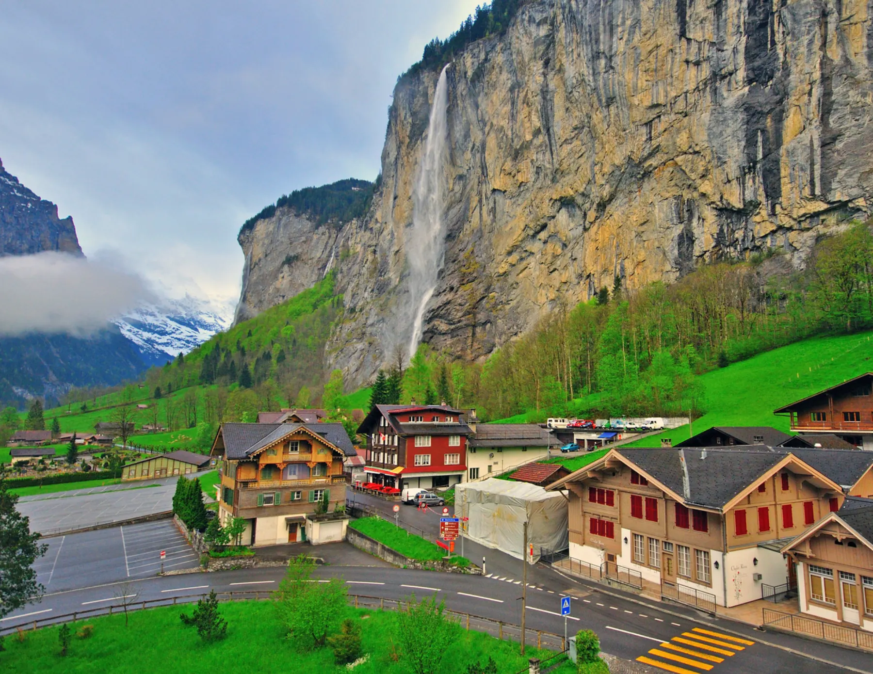 Houses set against wooded hills and a waterfall
