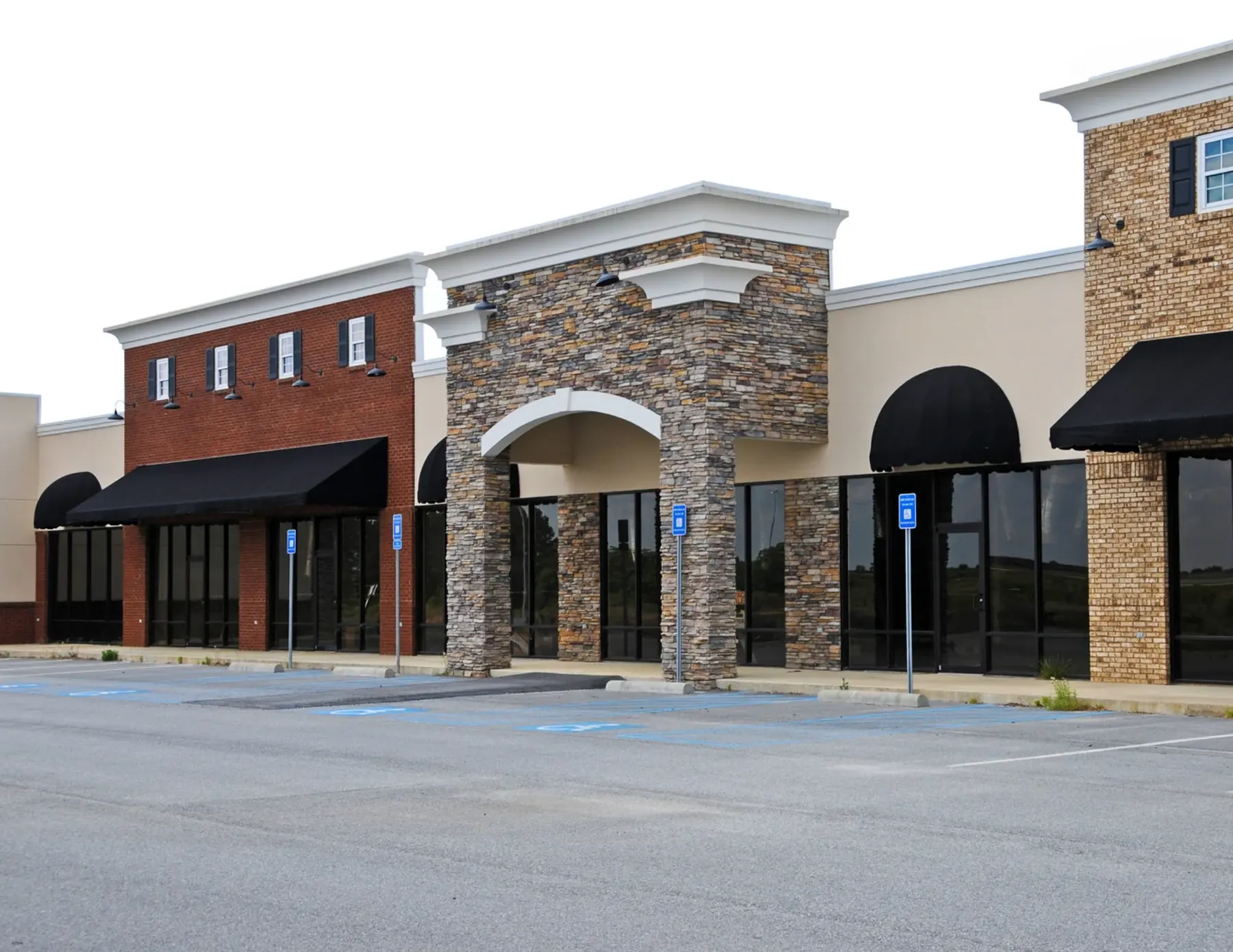 Stone and stucco retail plaza with storefronts and parking